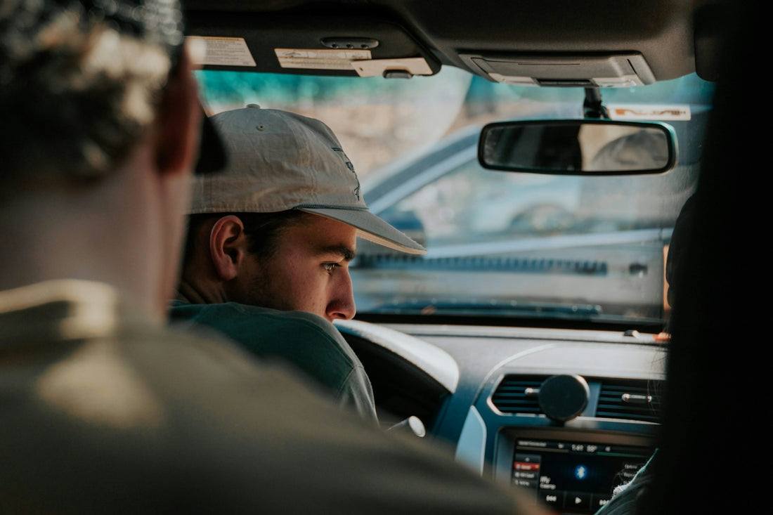 a man driving a car while wearing a hat