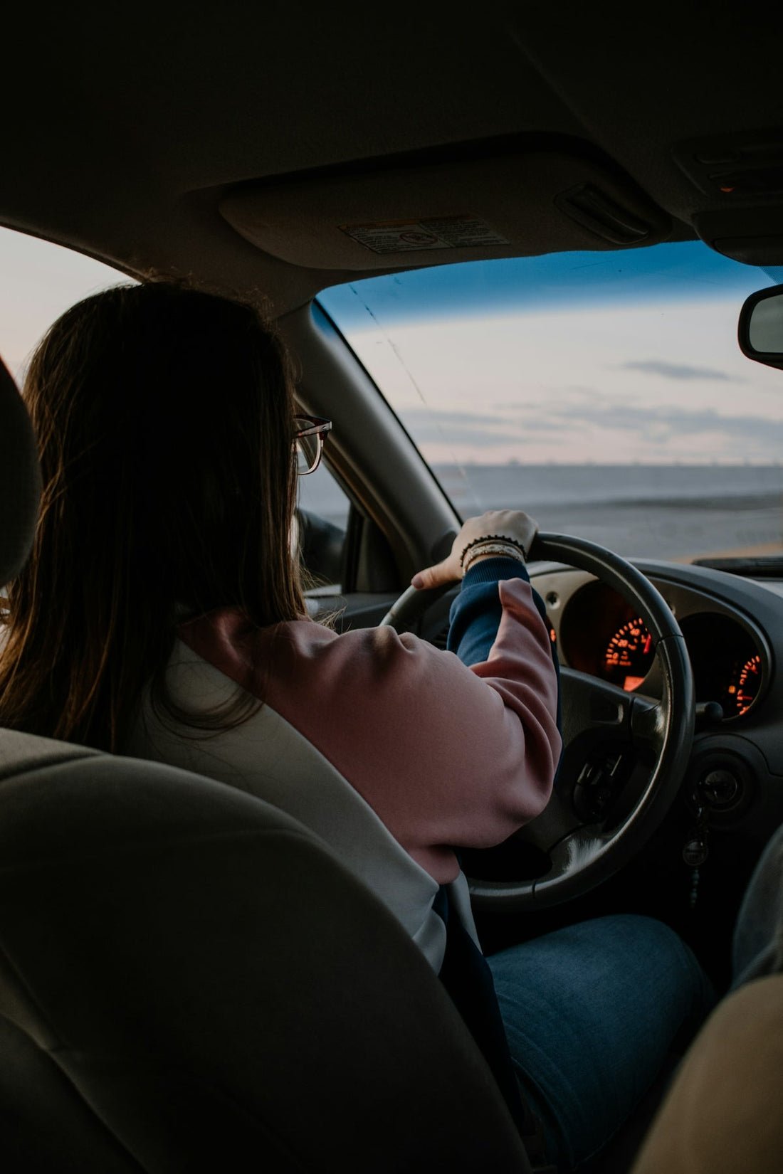 Learner driver practising for her UK driving test, staying calm and confident behind the wheel at dusk